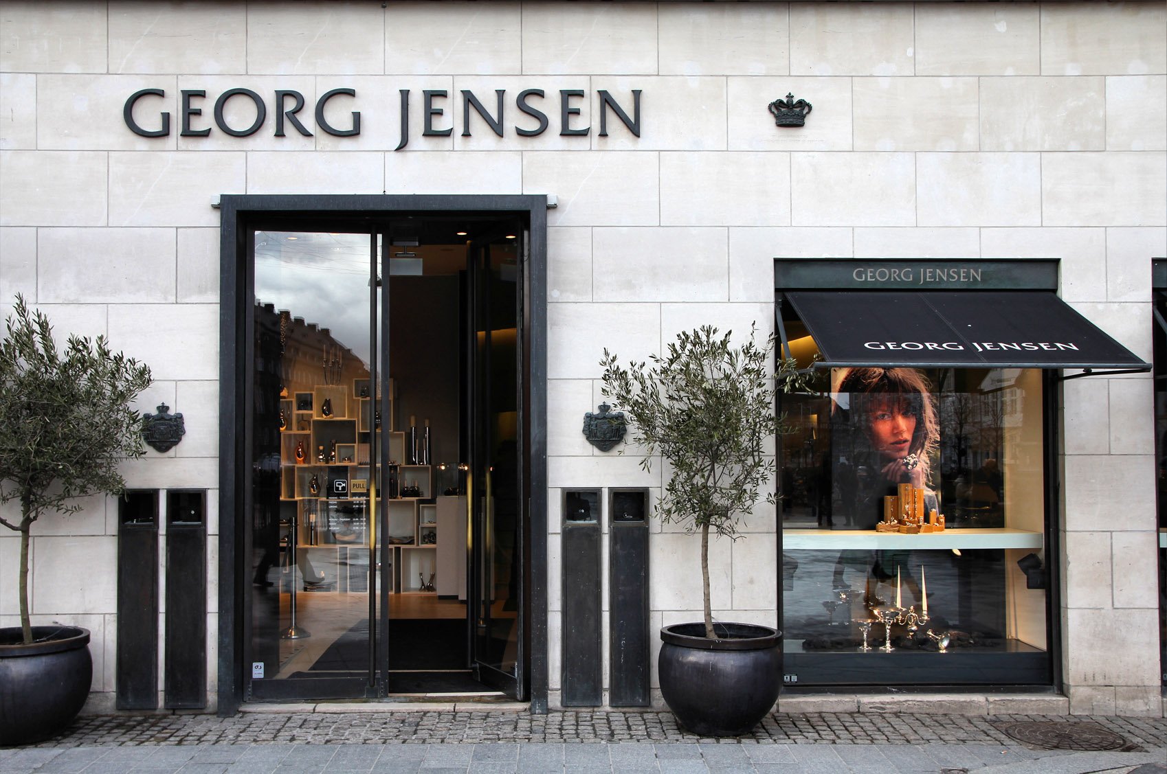 Eksteriør af en Georg Jensen-butik med stort udstillingsvindue og brandskiltning over indgangen.