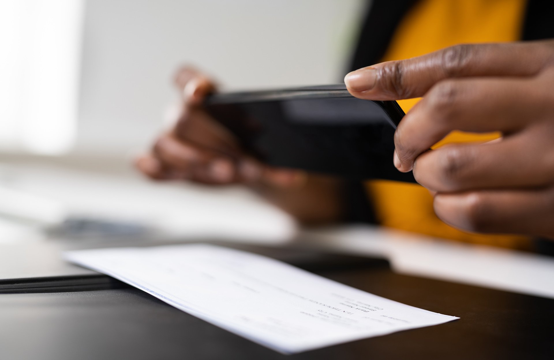 Person, der tager et billede af en check med en smartphone til mobilindbetaling.
